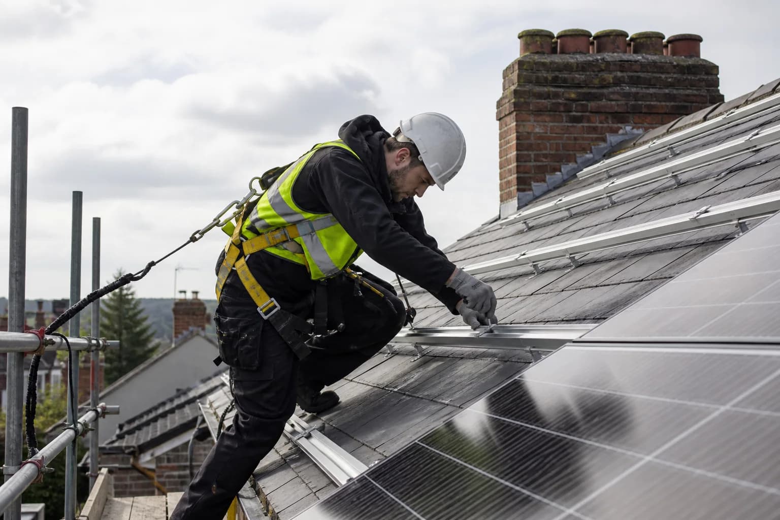Harnessed solar installer on a British roof beside insurance and certification symbols